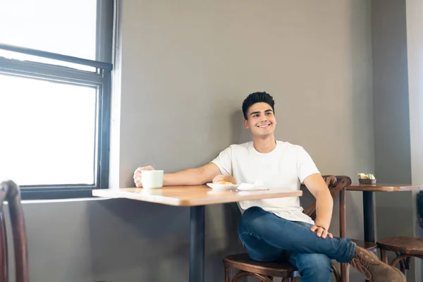 Bom Jovem Olhando Desfrutando Uma Xícara Café Pouco Pão Doce — Fotografia de Stock