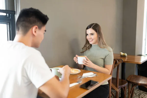 美しい若い女性と彼女のボーイフレンドは パン屋でコーヒーといくつかのペストリーのカップを楽しんで — ストック写真