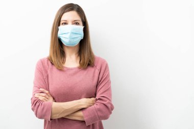 Coronavirus sırasında kolları çapraz cerrahi maske takan 40 'lı yaşlarda bir kadın.