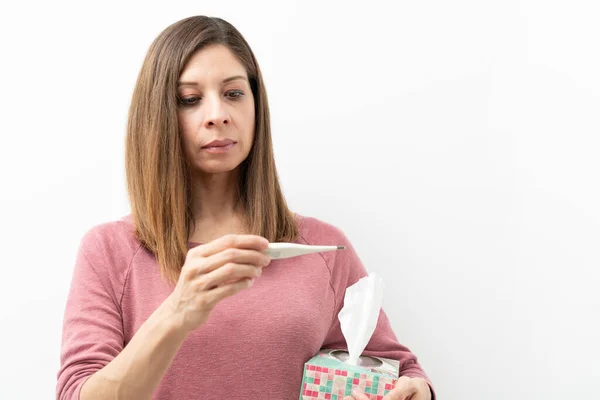 白人妇女拿着一盒纸巾 看着温度计 检查发烧情况 — 图库照片