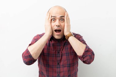 30 'lu yaşlarda, ağzı açık ve elleri yüzünde şoka uğramış bir adamın portresi.