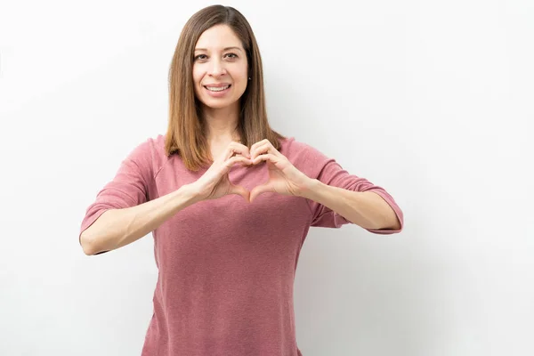 Atraktivní Běloška Která Rukou Vytváří Tvar Srdce Usmívá Studiu — Stock fotografie