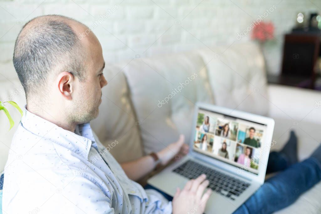Bald man doing a video call with some friends and family while using a laptop computer at home