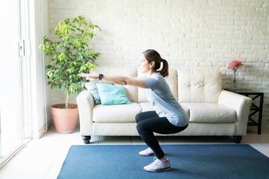 40 'lı yaşlarda aktif bir kadının evde çömelmesi ve spor yapması.