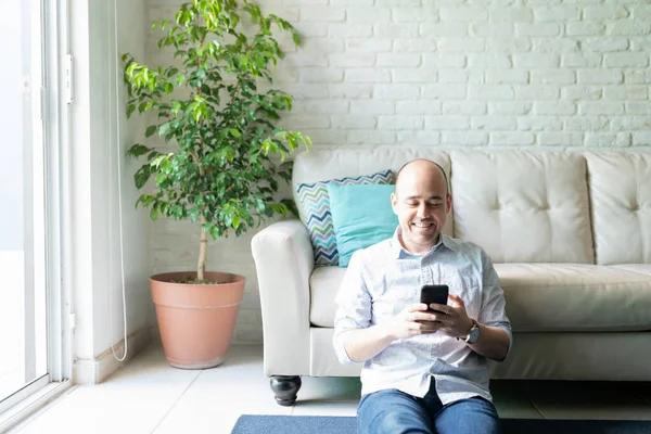 白人男子穿着休闲装坐在地毯地板上 在家里用智能手机进行社交 — 图库照片