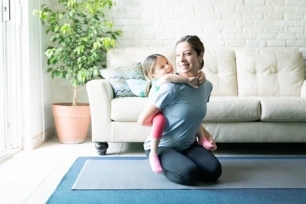 Sevgi Dolu Bir Anne Kızını Sırtında Taşırken Evde Egzersiz Yaparken — Stok fotoğraf