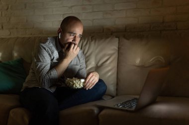 Stresli adam geceleri kulaklık takıp dizüstü bilgisayarında şüpheli bir film izlerken tırnaklarını yiyor.
