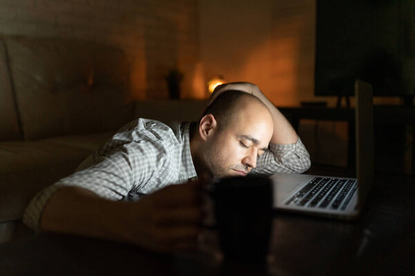 Уставший человек засыпает после работы допоздна за ноутбуком из дома
