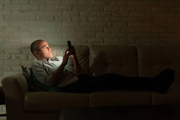 Perfil Homem Caucasiano Deitado Sofá Casa Olhando Para Seu Smartphone — Fotografia de Stock