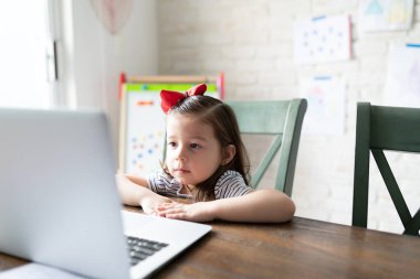 Evden online ders alırken dizüstü bilgisayara bakan beyaz bir kız.