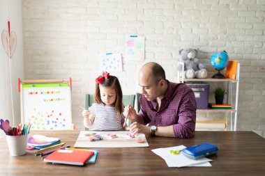 Bir baba ve kızını evde eğitim alırken ve alçı figürleri çizerken geniş bir bakış açısı var.