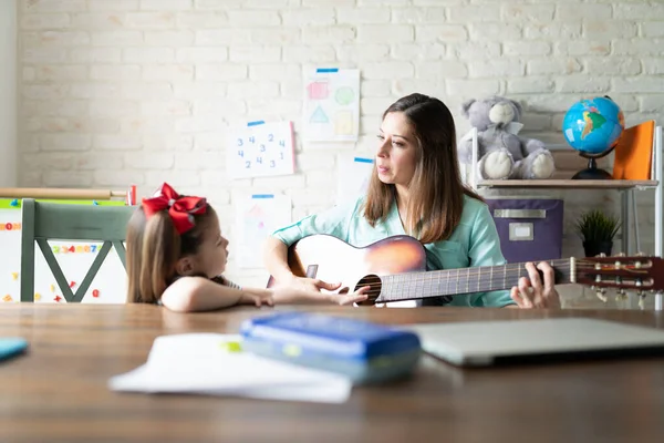 美しいですお母さん遊びギターと教育音楽へ彼女の小さな女の子に家 — ストック写真