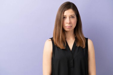 Güzel bir esmerin portresi üzgün görünüyor ve bir stüdyoda mor bir arka planda somurtuyor.