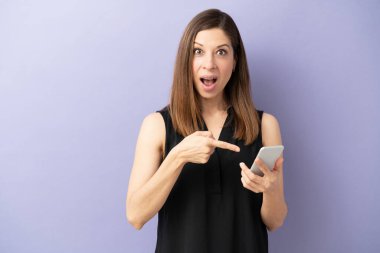 Stüdyoda şaşırtıcı bir şey gördükten sonra akıllı telefonunu işaret eden şok olmuş bir kadın.