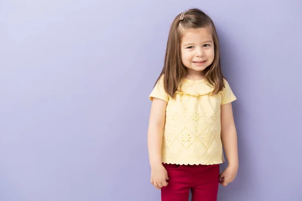 良い見て小さいブルネット女の子見ます幸せと笑顔でスタジオでともに紫の背景 — ストック写真