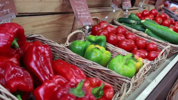 Um shot de uma cesta de pimentas vermelhas e verdes em um mercado de madeira — Vídeo de Stock