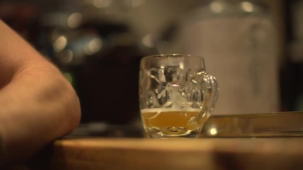 Знімок келиха пива поруч з рукою чоловіка на барі в пабі — стокове відео