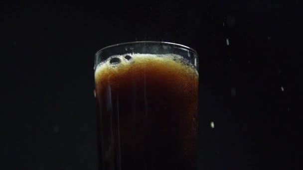 Um tiro super lento do gelo que está sendo deixado cair em um copo de cola — Vídeo de Stock