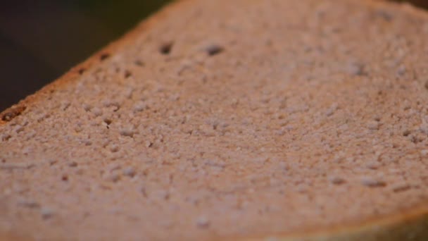 Крупный план ножа, намазывающего масло на кусок хлеба — стоковое видео