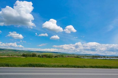 Yeşil bir tarlanın güzel manzarası, güneşli bir günde beyaz bulutlu mavi gökyüzü, doğa arka planı..