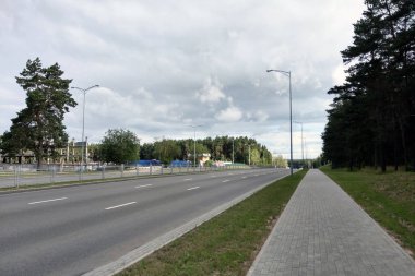 Yolun kenarında ağaçlar olan geniş ve boş bir yol manzarası.