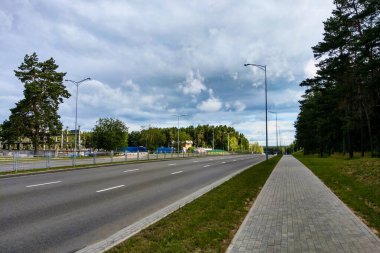 Yolun kenarında ağaçlar olan geniş ve boş bir yol manzarası.