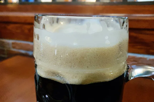 Горщик темного пива з піною на столі, вибірковий фокус . — стокове фото