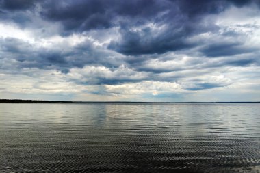 su, atmosferik arka plan üzerinde kara bulutların arasından parlayan ay.