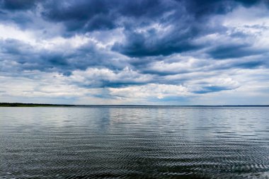 su, atmosferik arka plan üzerinde kara bulutların arasından parlayan ay.