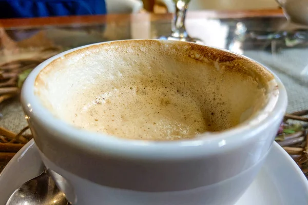 Een kop koffie in een wit kopje op houten achtergrond. — Stockfoto