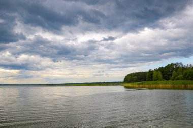 Bulutlu bir günde büyük bir göl ya da denizin kıyısında