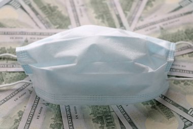 Solunum yollarının virüsten korunmasının bir sembolü olarak dolarların üzerindeki tıbbi maske. Kopyalama için bir yer var.