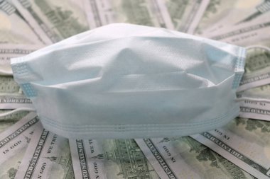 Solunum yollarının virüsten korunmasının bir sembolü olarak dolarların üzerindeki tıbbi maske. Kopyalama için bir yer var.