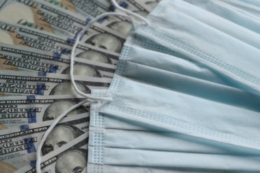 Solunum yollarının virüsten korunmasının bir sembolü olarak dolarların üzerindeki tıbbi maske. Kopyalama için bir yer var.