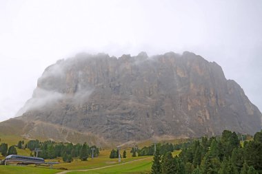 Dolomites Alplerindeki dağ köyünde sisli bir sabah manzarası, seçici bir odak noktası.