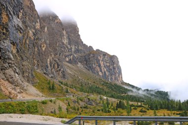 Dağlarda kaygan ıslak bir yol var. Dolomitlerde puslu bir sabah. İtalya. Seçici odak