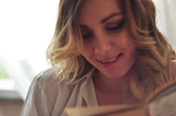 Genç güzel kadın tarafından ahşap masa oturma ve kitap okuma