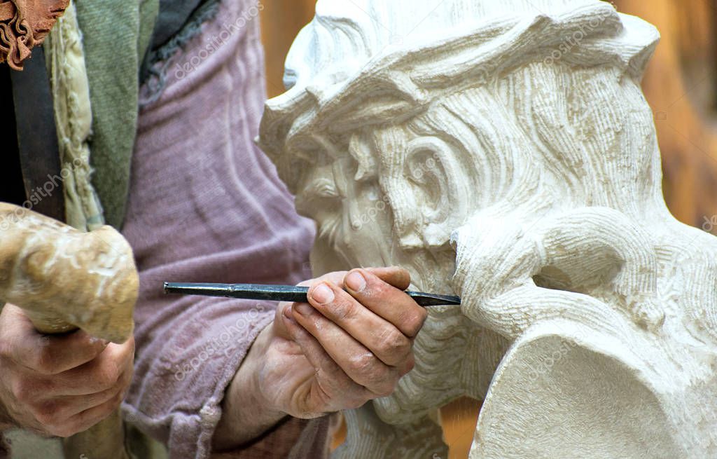 Sculptor stone carving a Christ with the crown of thorns. Professional craftsman, an artist working manually.