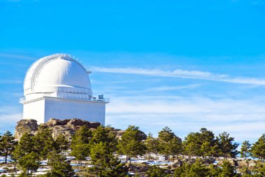 View of Calar Alto Observatory at the snowy mountain top in Almeria, Andalusia, Spain, 2019. Sky passing through against the domes. clipart
