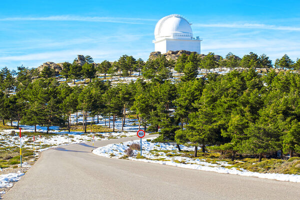 Road to Calar Alto Observatory at the snowy mountain top in Almeria, Andalusia, Spain, 2019. Sky passing through against the domes.
