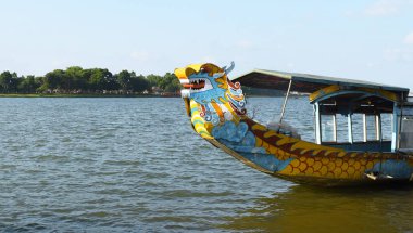 Houng Nehri 'nin pürüzsüz yüzeyinde yüzen turist çekici ejderha teknesi, Hue' deki parfüm nehri, Vietnam 'daki dünya kültür mirasının barışçıl atmosferine sahip.