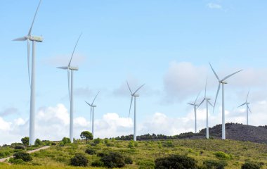 Rüzgâr değirmenleri bulutlu gökyüzüne karşı İspanyol rüzgâr çiftliğinde dönüyor. Metin için alanı kopyala