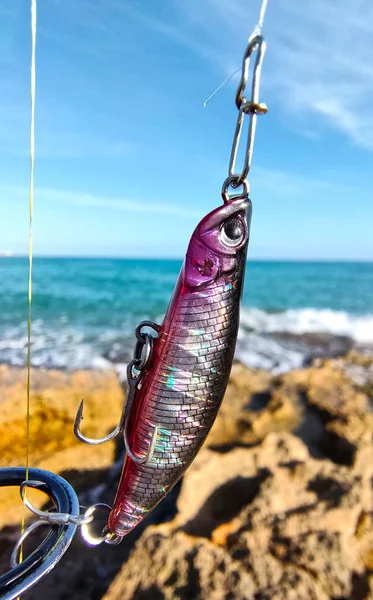 Close-up fishing lure in a fishing rod against the blue mediterranean sea. Macro fishing bait. Background,sport and recreation.