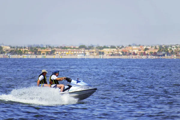 La manga, Murcia, Spanien, 2 augusti 2010: Två äldre turist män njuter av en vattenskoter rida på en varm sommareftermiddag i de grunda vattnen i de spanska kusterna. — Stockfoto