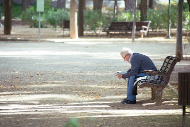 Albacete, İspanya, 18 Ocak 2020: Ahşap bir bankta oturan beyefendi Abelardo Sanchez parkında gazete okuyordu..
