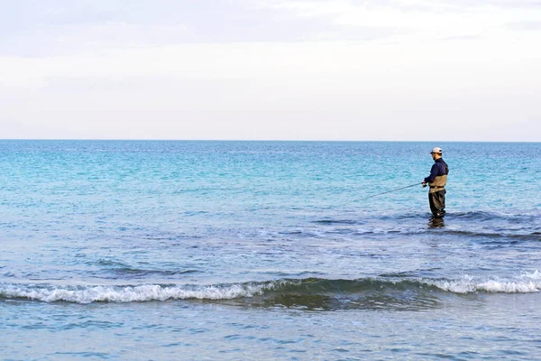 Pescador de pé na praia lançou a vara de peixe. Sportsman detém uma vara de pesca e carretel em um peixe viciado. Spin Passatempo pesca pegar um peixe na praia em Murcia, Espanha, 2020 — Fotografia de Stock