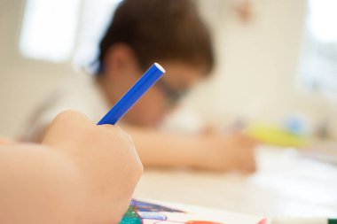 Çocuk canlı renkler üzerine bir kağıda soyut şekiller çiziyor. Sanat eğitimi sınıfındaki nesnelerin gölgeleri vasıtasıyla soyut formu tanıtmak. Yakın çekim görünümü