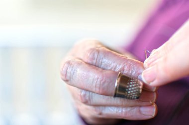 İğne ipliği, kadının ellerinin iğneye iplik çektiği HD yakın çekim videosu. Ürün eksikliğinden dolayı koronavirüs için kendi maskelerini yapıyorlar.