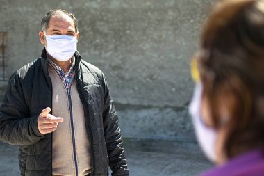 İki kişi güvenlik mesafesini korumaktan, koronavirüs için koruma maskesi takmaktan ya da şehirde covid-19 virüsü salgınından bahsediyor. Corona virüsü, Covid-19, virüs salgını veya sosyal uzaklık kavramı.
