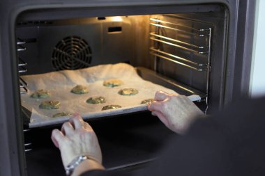 Genç bir kadın covid 19 sırasında fırında kakao bisküvisi pişiriyor ya da izolasyonda koronavirüs pişiriyor..